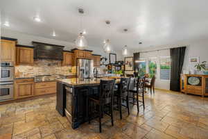 Kitchen featuring brown cabinetry, stainless steel appliances, a breakfast bar area, tasteful backsplash, and recessed lighting
