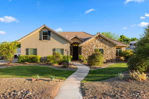 View of front facade featuring stucco siding, a front yard, a tiled roof, and stone siding