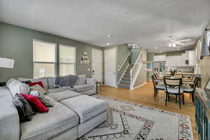 Living area with stairway, light wood-style floors, ceiling fan, recessed lighting, and a textured ceiling