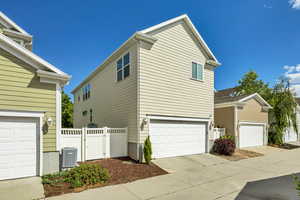 View of side of home with concrete driveway, a gate, and an attached garage