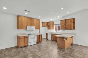 Kitchen featuring open shelves, a peninsula, recessed lighting, white appliances, and brown cabinets