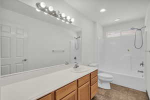 Bathroom with shower / washtub combination, vanity, recessed lighting, and dark tile patterned floors