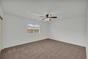 Carpeted spare room featuring baseboards and ceiling fan