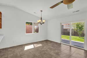 Unfurnished dining area featuring lofted ceiling, a chandelier, tile patterned floors, and a ceiling fan