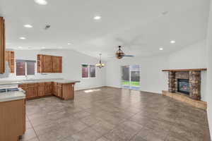 Kitchen featuring brown cabinets, tile countertops, a peninsula, recessed lighting, and a fireplace