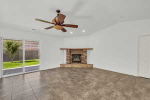 Unfurnished living room with vaulted ceiling, a stone fireplace, recessed lighting, dark tile patterned floors, and a ceiling fan