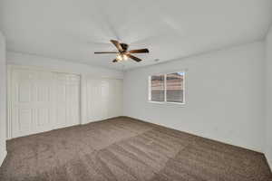 Unfurnished bedroom with two closets, carpet, and ceiling fan