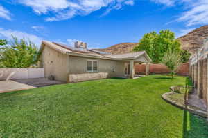 Back of property with a patio area, a fenced backyard, stucco siding, and solar panels
