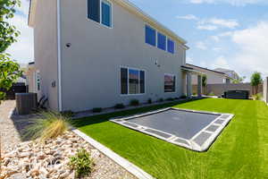 Back of house with a fenced backyard, a hot tub, and stucco siding