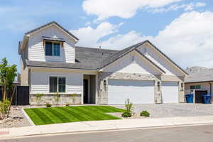 View of front of property with stone siding, decorative driveway, board and batten siding, and a garage