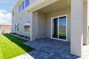 Entrance to property with a patio area, a yard, and stucco siding