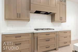 Kitchen featuring light countertops, exhaust hood, light wood-style flooring, and tasteful backsplash