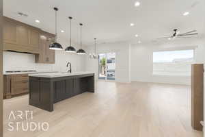 Kitchen featuring light wood-style floors, light countertops, a kitchen island with sink, recessed lighting, and tasteful backsplash