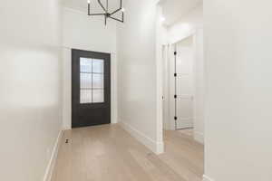 Entrance foyer with light wood-style flooring and a chandelier