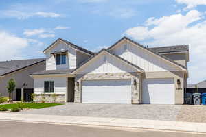 View of front of property with decorative driveway, an attached garage, stone siding, and board and batten siding