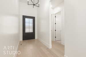 Entrance foyer with light wood-type flooring and a chandelier