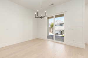 Unfurnished dining area featuring light wood-type flooring and a chandelier