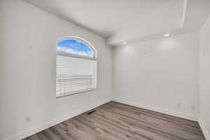 Spare room featuring vaulted ceiling, wood finished floors, and recessed lighting