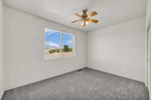Empty room with carpet, a ceiling fan, and a textured ceiling