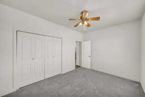 Unfurnished bedroom featuring carpet floors, a closet, and a ceiling fan