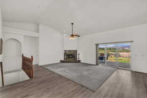 Unfurnished living room with ceiling fan, wood finished floors, vaulted ceiling, and a premium fireplace