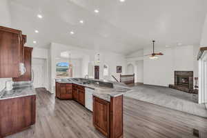 Kitchen with recessed lighting, a fireplace, light wood finished floors, a ceiling fan, and arched walkways