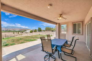 Fenced backyard with a patio, ceiling fan, outdoor dining area, and a mountain view
