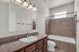 Full bath featuring tiled shower / bath combo, vanity, and a textured ceiling