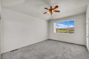 Carpeted empty room featuring a textured ceiling and a ceiling fan