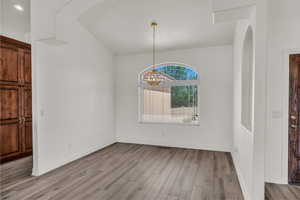 Unfurnished dining area with a chandelier, light wood-style floors, and arched walkways