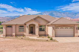 View of front facade featuring driveway, a garage, stucco siding, a mountain view, and a tile roof