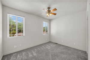 Carpeted spare room featuring a textured ceiling and ceiling fan