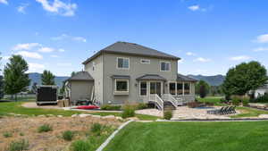 Back of property featuring a mountain view, a patio, stucco siding, and a shingled roof