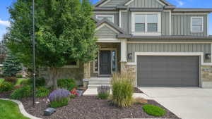 Craftsman house with stone siding, board and batten siding, driveway, and a garage