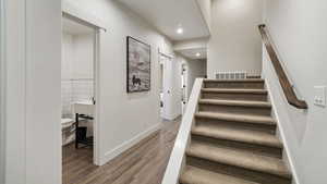 Staircase featuring wood finished floors and tile walls