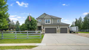 View of front of house featuring an attached garage, concrete driveway, board and batten siding, and stone siding