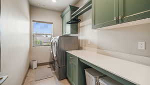 Laundry area with washing machine and dryer, cabinet space, and light tile patterned floors
