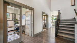 Foyer with dark wood-style flooring, stairs, french doors, ceiling fan, and a high ceiling