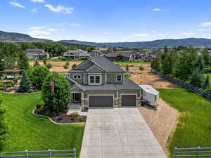 View of front facade with board and batten siding, driveway, stone siding, a garage, and a residential view