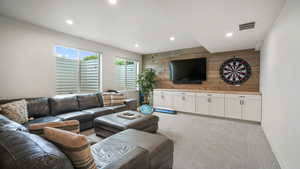 Living room featuring wooden walls, light carpet, an accent wall, and recessed lighting