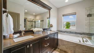 Full bathroom with double vanity, a stall shower, a bath, and recessed lighting