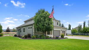 View of front of house featuring driveway, an attached garage, stone siding, and board and batten siding