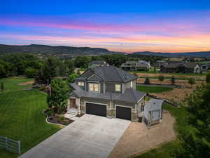 View of front facade with concrete driveway, stone siding, an attached garage, board and batten siding, and a mountain view