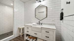 Full bathroom with tile walls, a walk in shower, vanity, and wood finished floors