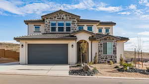 Mediterranean / spanish home with stone siding, concrete driveway, an attached garage, and a tiled roof