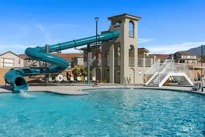 Community pool featuring a water slide, stairway, a residential view, and a patio