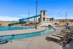 Community pool with a water slide, a patio area, and stairway
