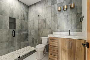 Bathroom with tile walls, vanity, a stall shower, and tile patterned flooring