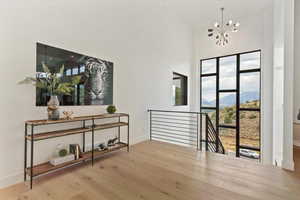 Hall featuring an upstairs landing, a chandelier, wood finished floors, and a high ceiling