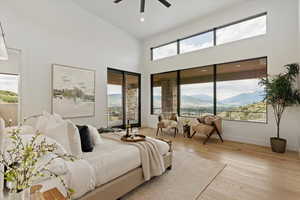Bedroom with a mountain view, light wood-type flooring, a towering ceiling, a ceiling fan, and recessed lighting